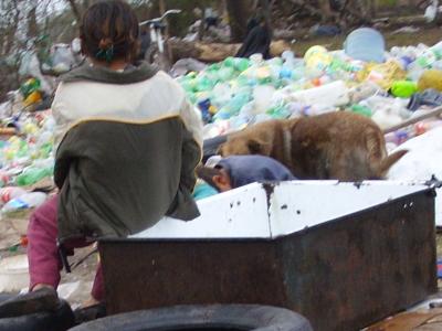 Un niño descansa con su perro en el basural mientras sus padres juntan plásticos y botellas